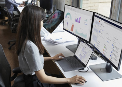 A woman working on laptop and monitors.