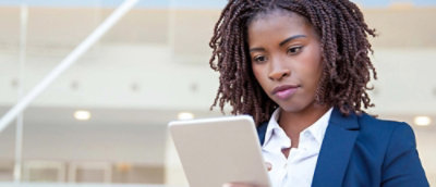 Person standing indoors and using a tablet in a modern office or public workspace setting.