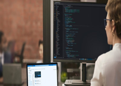 An employee working on laptop and monitor.