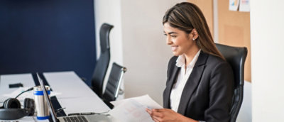 Person seated at office desk reviewing documents on computer