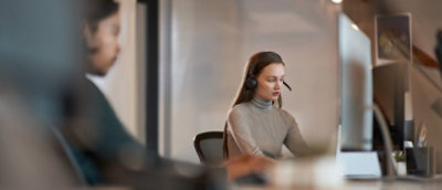 A person wearing headphones and glasses while looking at a computer screen.