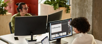 Team working at desktop computers while reviewing design and content on multiple screens in an office.