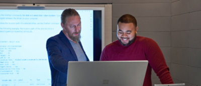 Two colleagues reviewing code together on a laptop in a meeting room
