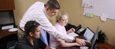 Team collaborating at desk reviewing information on a computer screen
