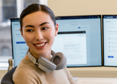 A woman working at a desk in an office wearing headphones