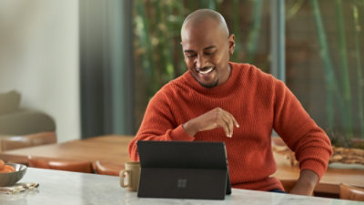 Person using a tablet at a kitchen table in a modern home workspace.