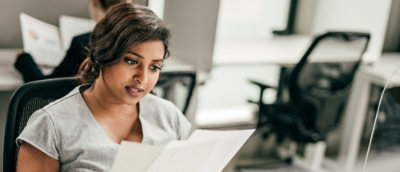 Person reading a document while seated in an office workspace.