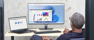 A man sitting at a desk with a computer and a laptop.