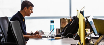 Person working at a desk with multiple monitors and office equipment.