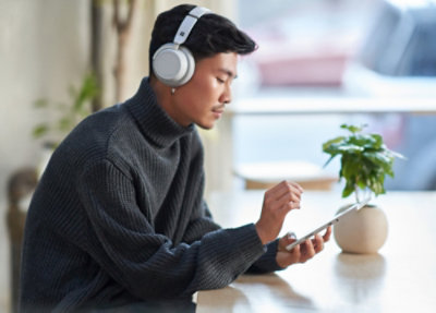 Person using headphones while working on a tablet at a desk