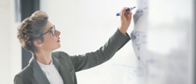 Person writing or presenting ideas on a whiteboard in a workspace.