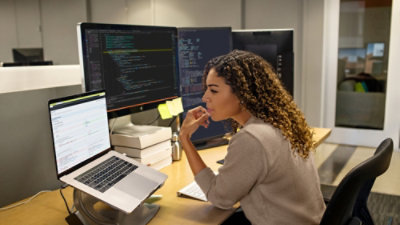 A woman sitting at a desk looking at a computer screen.