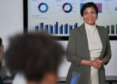 Presenter standing in front of charts during a meeting.