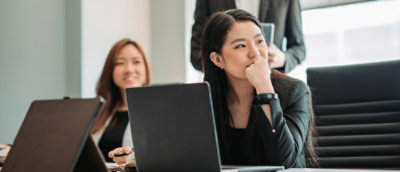 Person seated at a desk listening attentively during a presentation or meeting.