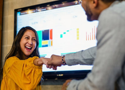 Team members reviewing analytics dashboards on a large screen with charts and graphs during a discussion.