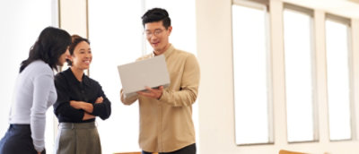 Three coworkers reviewing a laptop together.