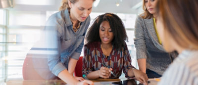 Team collaborating around printed documents and a laptop at a table.