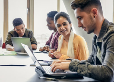 Colleagues collaborating around laptops at a table.