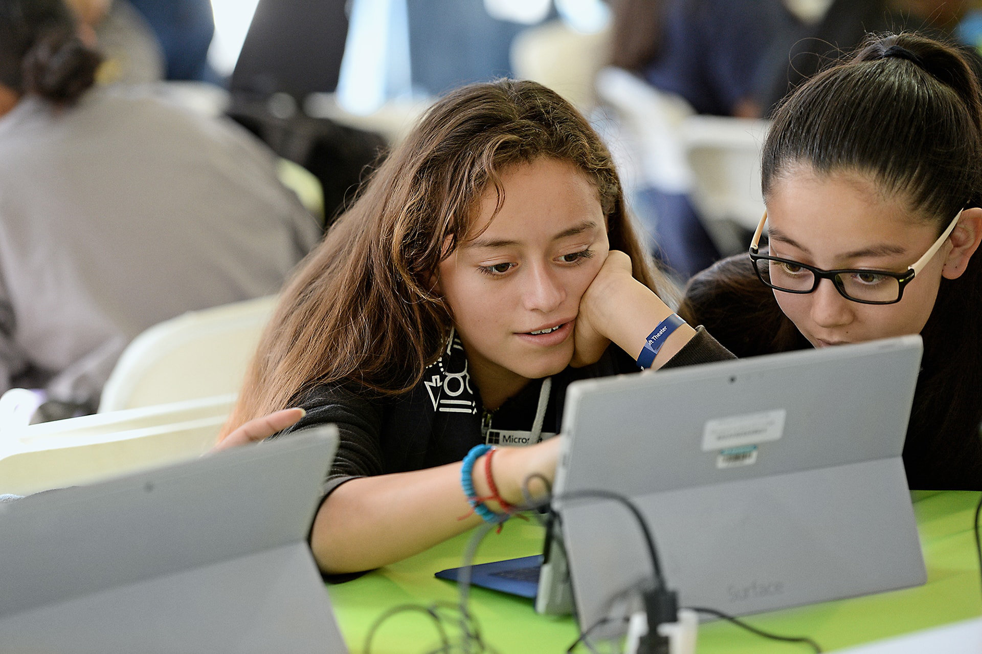 Two young students looking at a computer in a classroom.