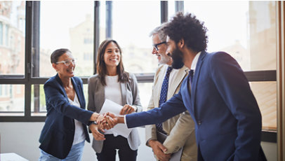 A group of four professionals greeting each other with two of them shaking hands.