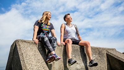 Kaksi henkilöä istumassa ulkona betonirakenteen päällä