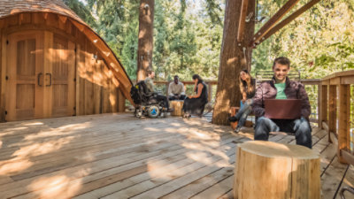Un árbol solitario crece en un lago con montañas en el fondo.