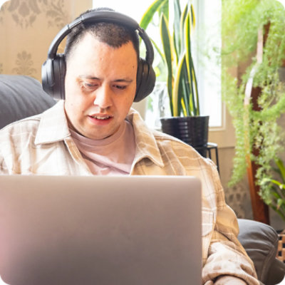Young adult with autism looking at laptop with headphones on.