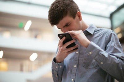 A man who has low vision, holds a mobile phone close to his face.