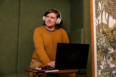 Man wearing headphones looking away from his laptop.