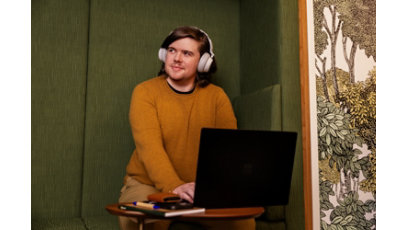 Man wearing headphones looking away from his laptop.