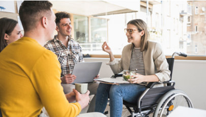 Jóvenes empresarios en una reunión en la oficina con una mujer sentada en una silla de ruedas.