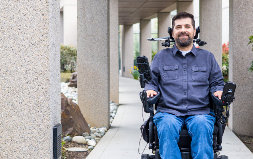 Une personne en fauteuil roulant traversant une passerelle extérieure.