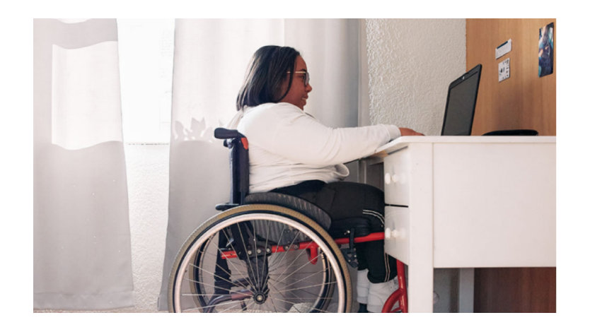 A young woman using a wheelchair in front of her laptop.