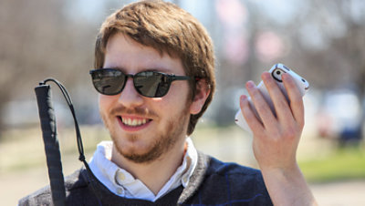 A man who is blind holding his phone up.