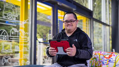 A young man with Down syndrome in the Microsoft Inclusive Tech Lab holds a tablet.
