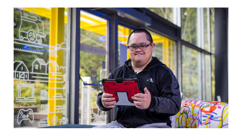 다운 증후군이 있는 청년이 Microsoft Inclusive Tech Lab에서 태블릿을 들고 있는 모습.