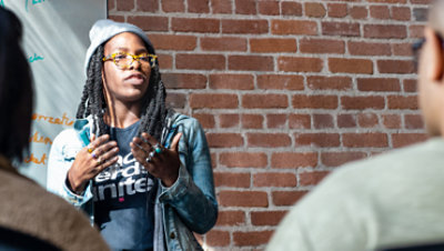 A woman delivers a speech in front of an audience.