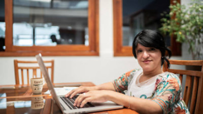 Woman using her computer with office as background.
