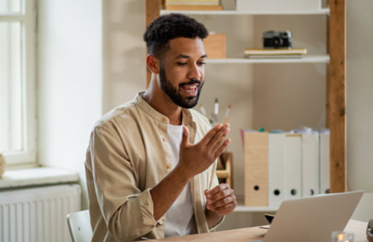  A man signing while using a laptop.