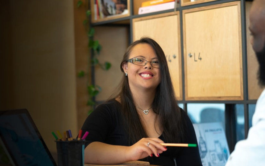  Two people talking and smiling in an office.