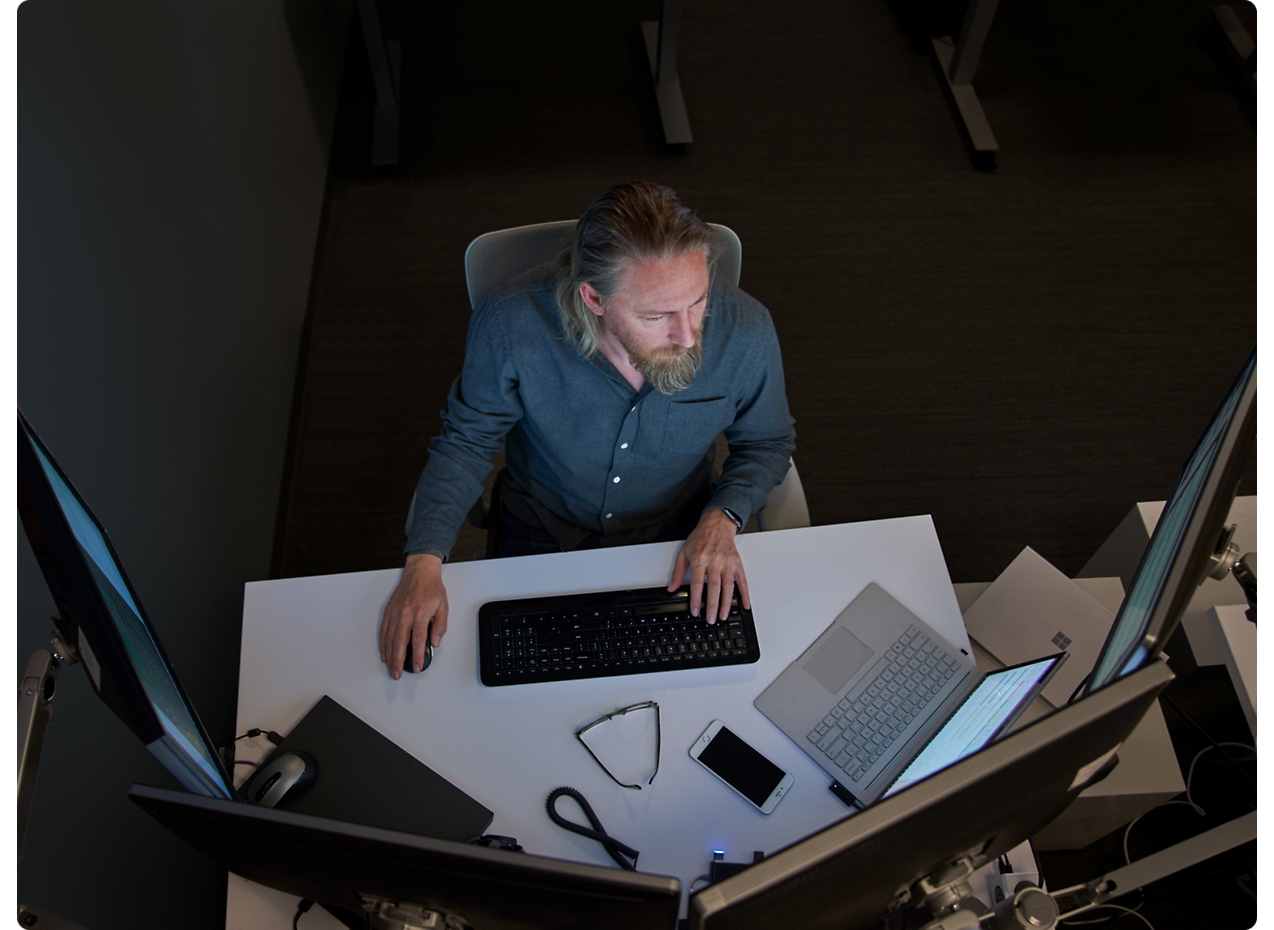 Deux hommes concentrés sur un écran d’ordinateur dans un environnement bureau, l’un avec le menton posé sur sa main.