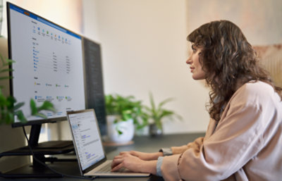Femme regardant un grand écran et travaillant avec un ordinateur portable
