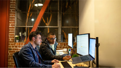 Deux hommes travaillent sur des ordinateurs dans un bureau.