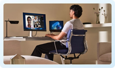 A person sitting at a desk with two computers.