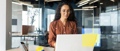 A woman wearing glasses works on a laptop
