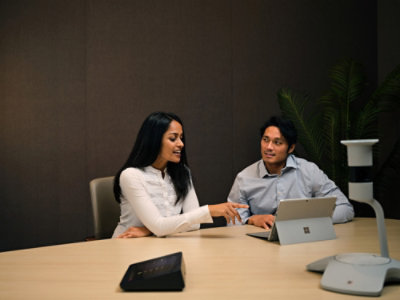 Two people reviewing Dynamics 365 sales data on laptop during a business meeting near a window