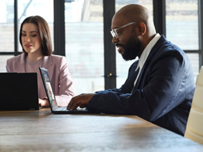 Professionals using laptops during a meeting in an office.