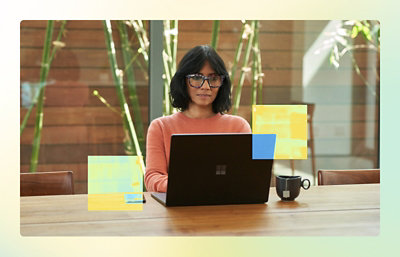 A woman wearing glasses and a pink shirt sitting in front of a laptop.