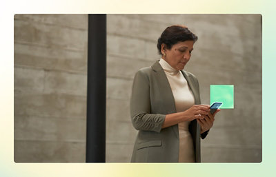 A woman in a suit looking at a cell phone.