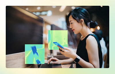 A person holding a phone and using a laptop.
